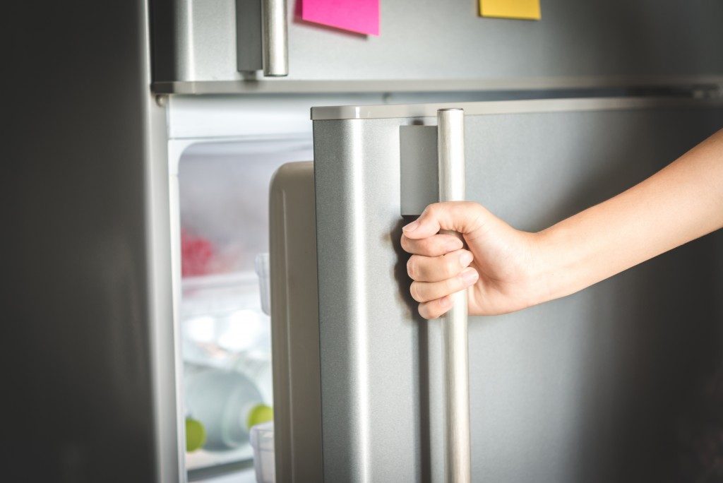Person opening a gray refrigerator