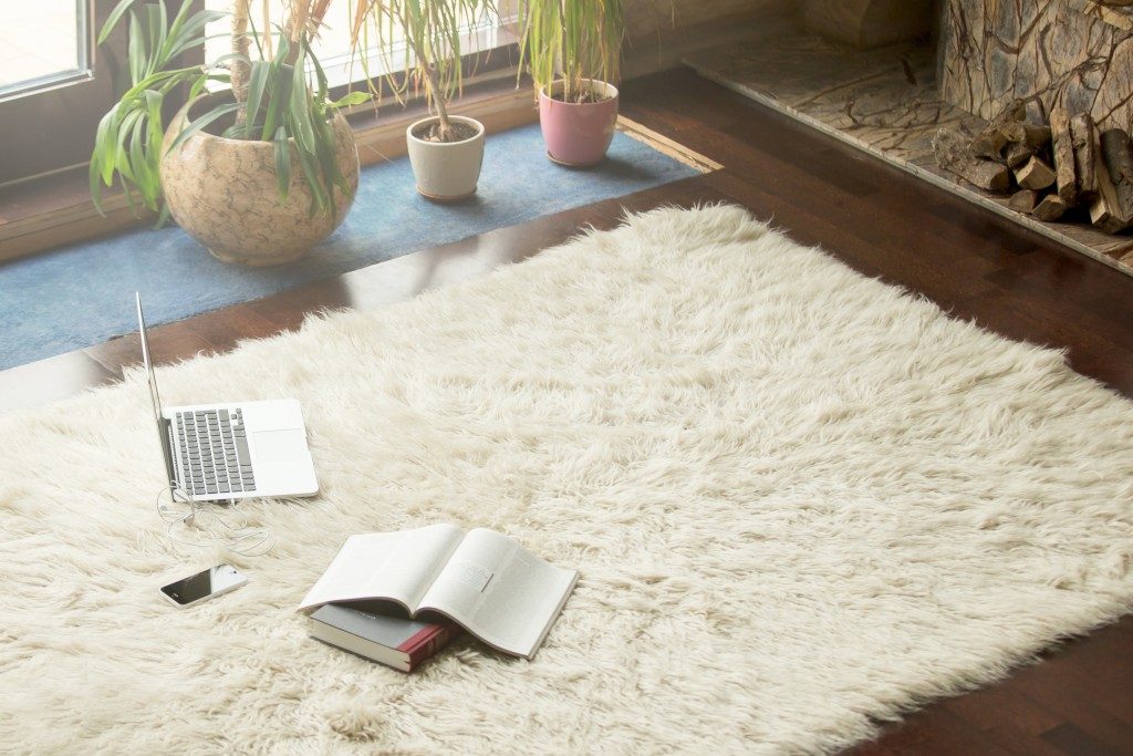 a laptop, phone, and books on top of a white carpet