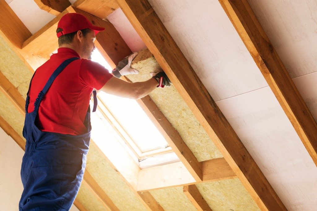 man installing insulation in a home's attic