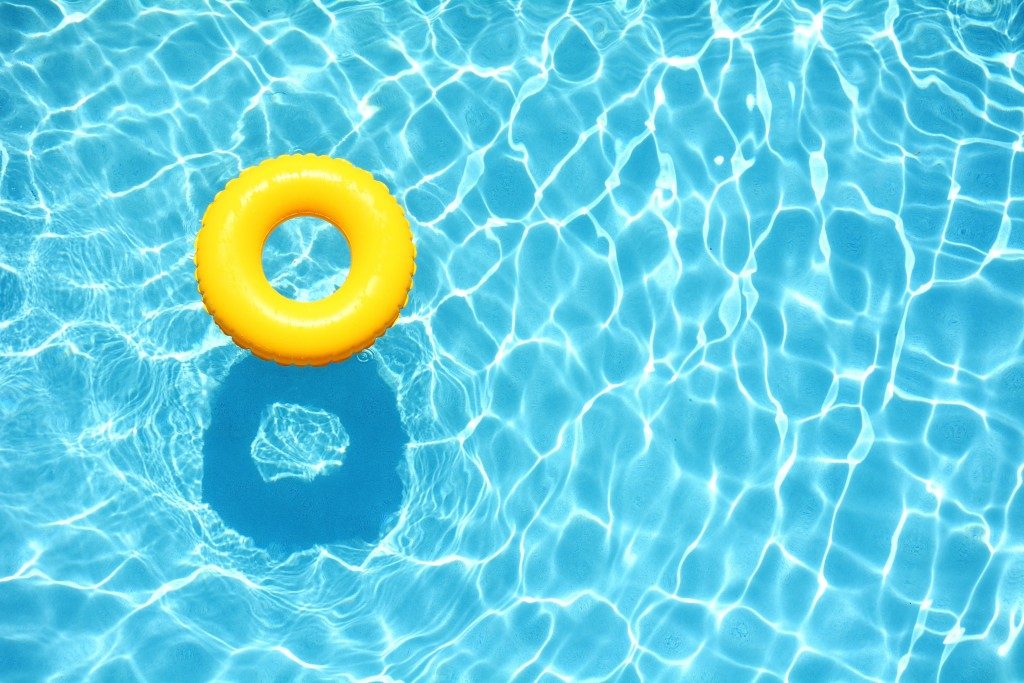 Yellow pool float, ring floating in a refreshing blue swimming pool
